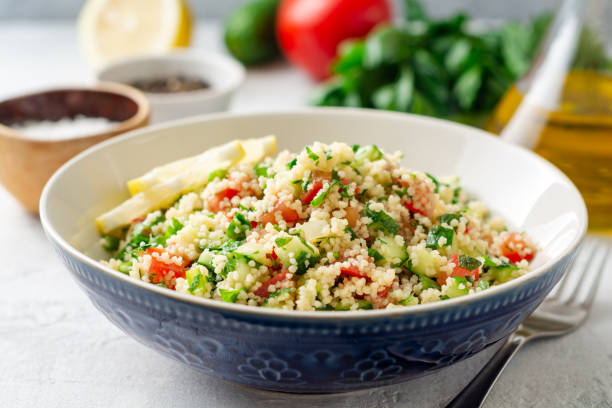 Traditional Arabic Salad Tabbouleh with couscous, vegetables and greens on concrete background Traditional Arabic Salad Tabbouleh with couscous, vegetables and greens on concrete background. Selective focus. couscous stock pictures, royalty-free photos & images