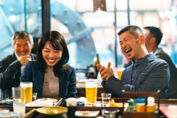 A group of Japanese people are having celebratory toast with beer in an Izakaya (Japanese style pub).