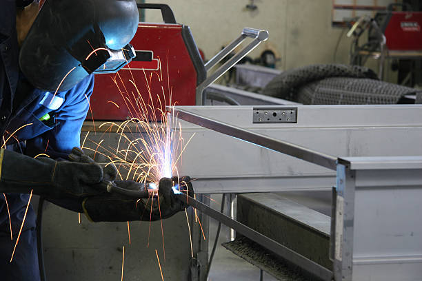 Sparks flying - welding steel frame Man welding a frame in a fab shop welding helmet stock pictures, royalty-free photos & images