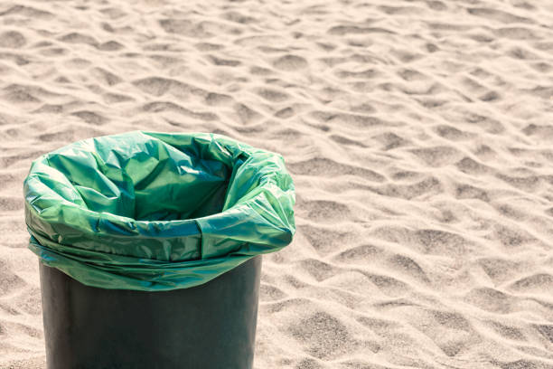 High angle view of plastic bag on trash can in beach sand - Clean beach concept. Rubbish bin in nature, environment backgrounds with copy space. Montenegro, Ulcinj beach coastline.