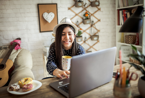 Young Asian girl working at a home with a laptop