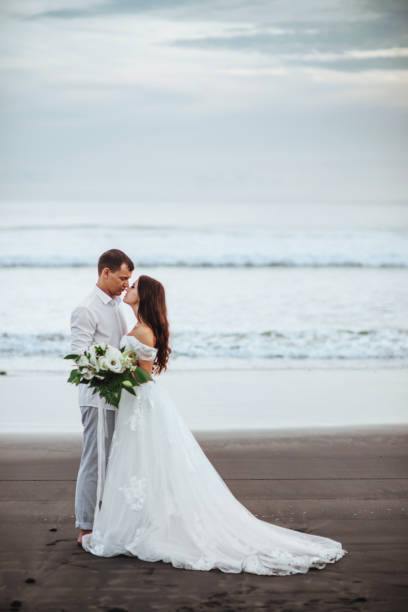 istock Elegant gorgeous bride and groom walking on ocean beach during sunset time. 1150762976