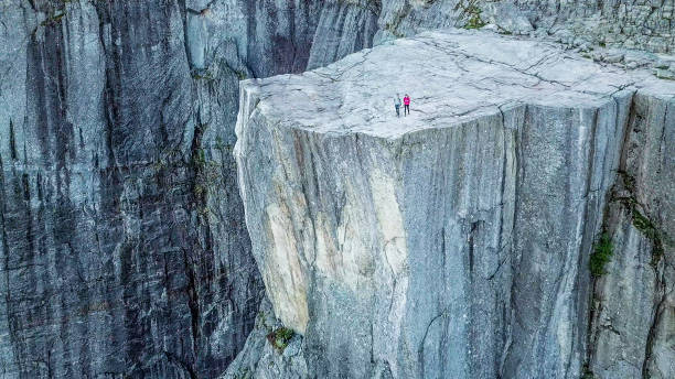 noruega-toma aérea de una pareja de pie en el borde de preikestolen - mountain mountain range norway fjord fotografías e imágenes de stock