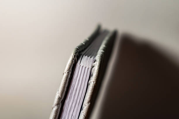 istock A book, a notebook with a checkered pattern on a wooden table in different poses. The cover is grey and soft with texture. Square patterns stitched with threads. Write notes in a diary. 1150768303