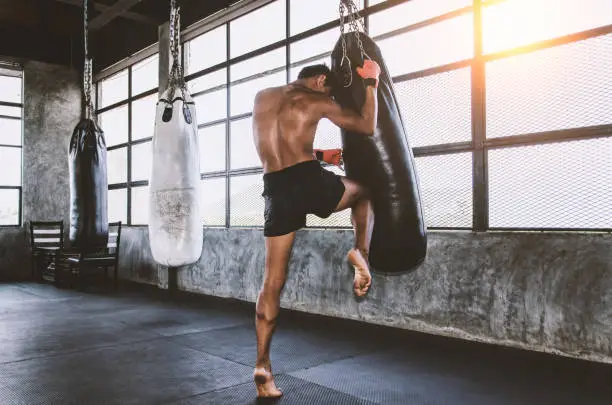 Photo of Muay thai fighter training in the gym with the punch bag