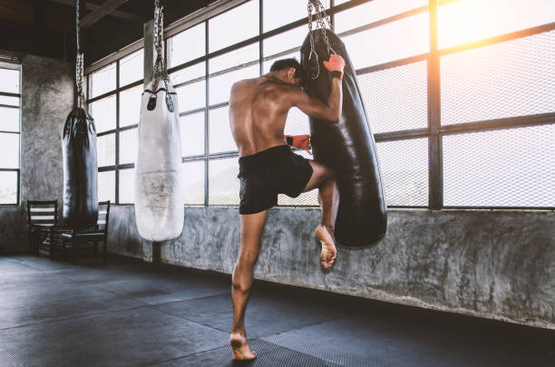 treinamento tailandês do lutador de muay na ginástica com o saco do perfurador - boxe desporto - fotografias e filmes do acervo