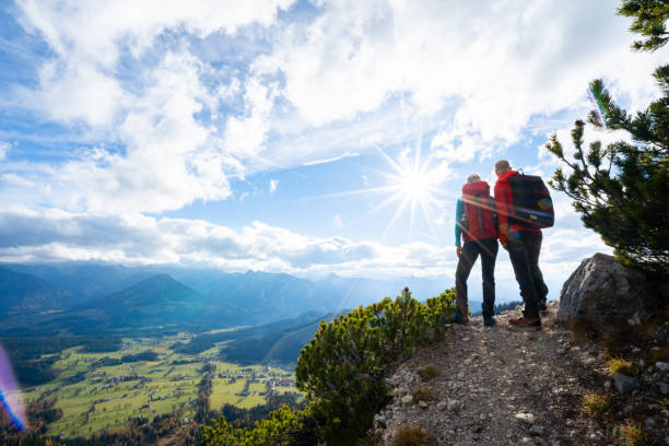 rear view sporty couple woman man together on  hiking path in mountains enjoying beautiful outlook on sunny autumn day starshapped sun