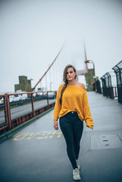 donna in maglione giallo cammina lungo ponte - bay bridge car traffic transportation foto e immagini stock