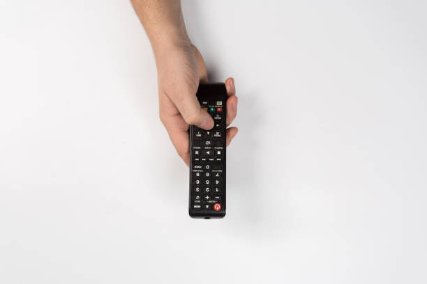 hand holding black remote control isolated on white background - changing channels imagens e fotografias de stock