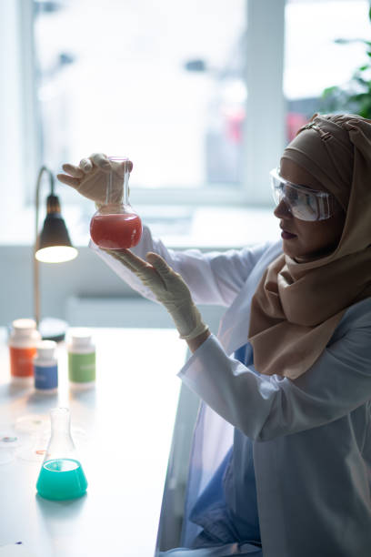 istock Chemist sitting in laboratory and looking at chemical glass 1150778313