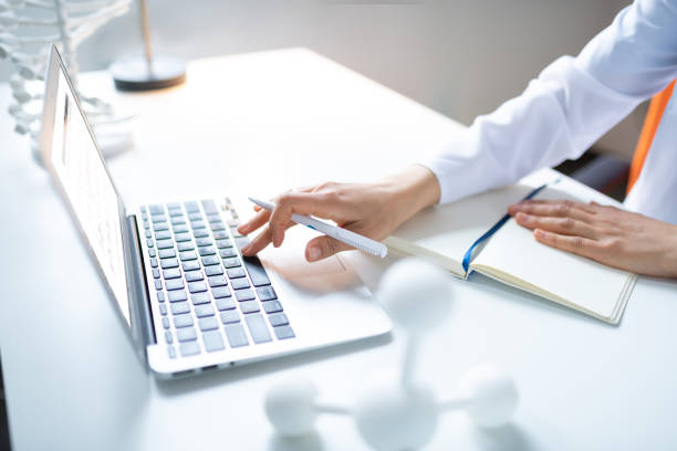 istock Scientist holding pen and typing something on laptop 1150778390