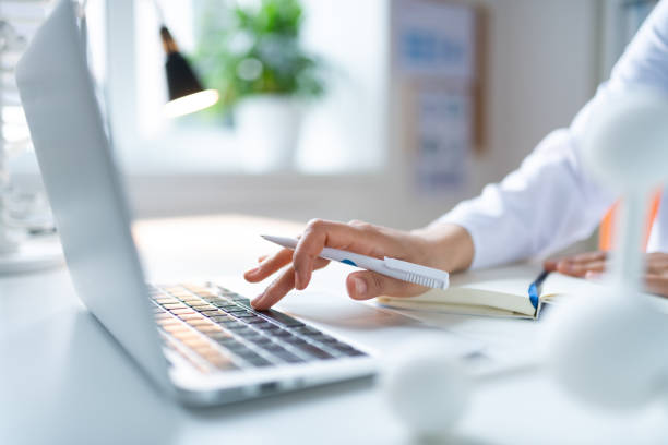Close up of female chemist holding white pen using laptop
