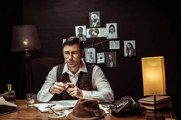 istock Pensive detective in glasses sitting at table and holding lighter in office 1150780133