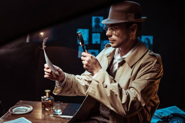 istock Detective in trench coat looking at photo through magnifier 1150780204