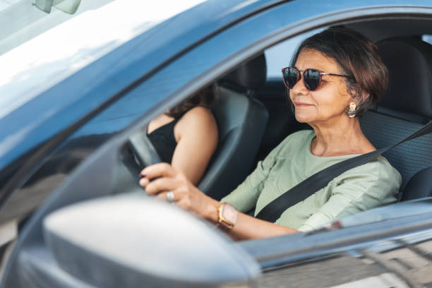 femme mature heureuse conduisant une voiture - security security system old blue photos et images de collection