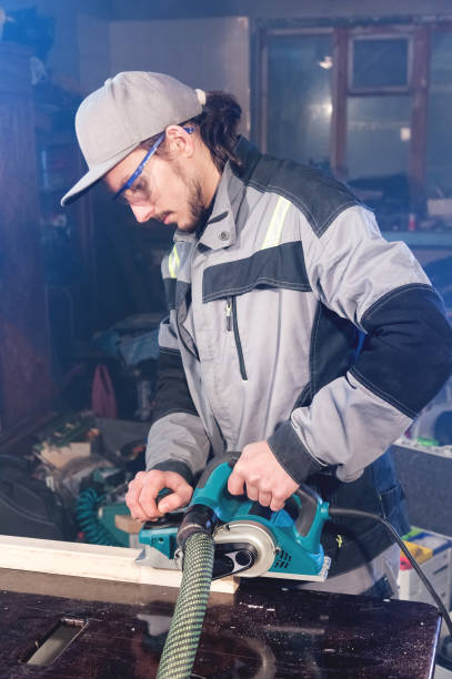 istock Portrait of a young carpenter working with an electrical plane in a home wood workshop 1150782849