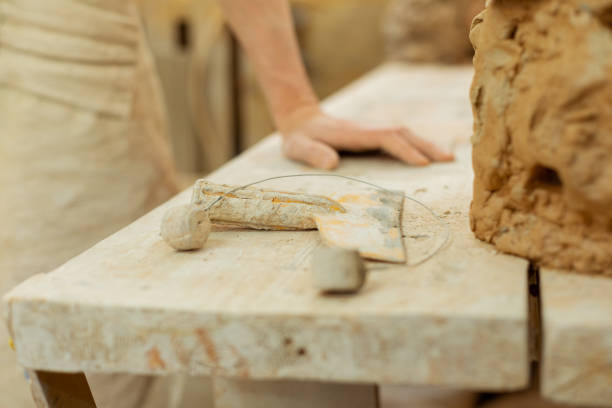 istock Man leaning on a working table covered in clay dirt 1150786340