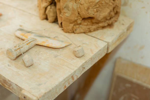 istock Dirty metal tool lying on a wooden table covered in clay layer 1150786362