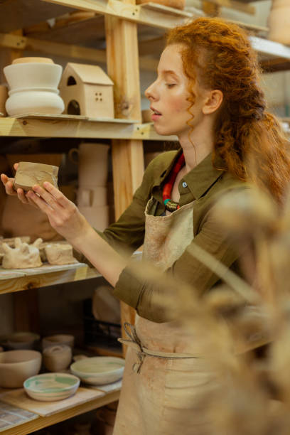 istock Attentive ginger girl enjoying different clay figures and pots 1150786370