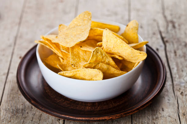 istock Mexican nachos chips in white bowl on brown ceramic plate. 1150788062