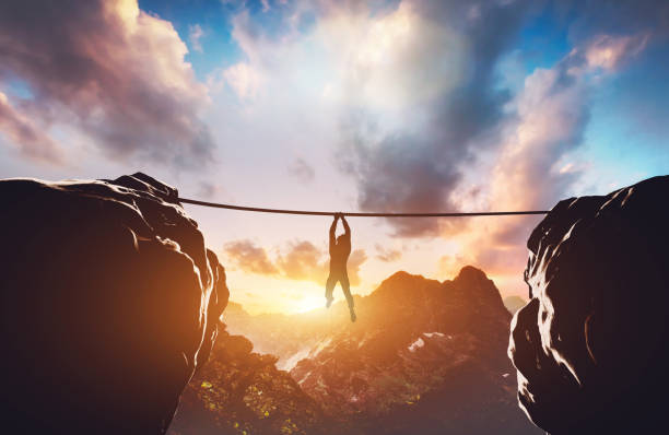 istock Man hanging on rope between two high mountains 1150788466