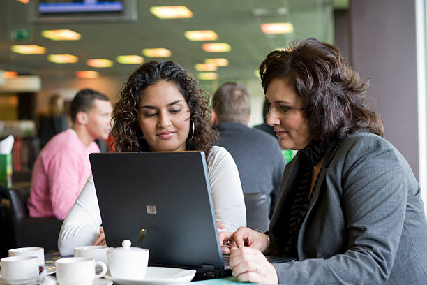 Two business woman looking at laptop screen.