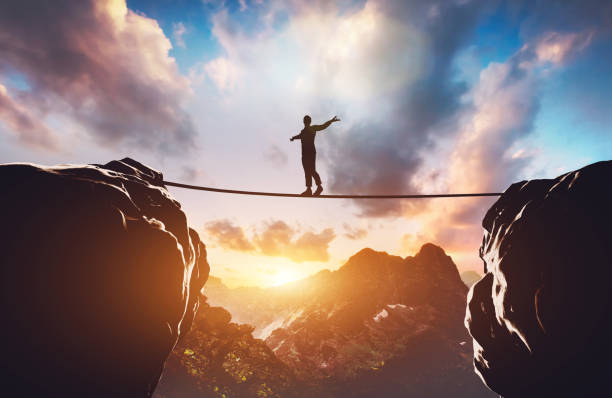 Man walking on rope between two high mountains Man walking on rope between two high mountains at sunset. Concept of taking a risk, adventure, motivation. 3d illustration tightrope stock pictures, royalty-free photos & images