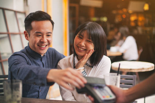 istock Asian young couple paying by smart phone in restaurant 1150793482