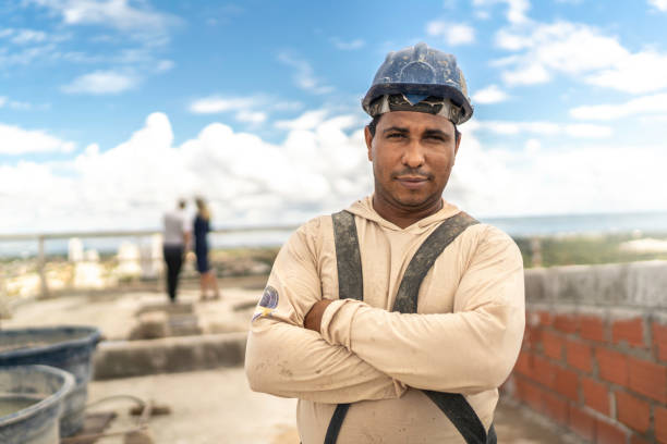 ouvrier de construction restant avec des bras croisés dans un chantier de construction - protective workwear bricklayer manual worker construction photos et images de collection