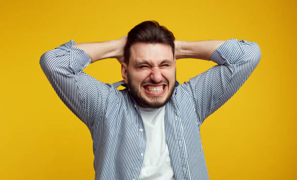 istock Young stressed young man clenches teeth in desperation, regrets about something, dressed in blue shirt, isolated over orange wall 1150800367