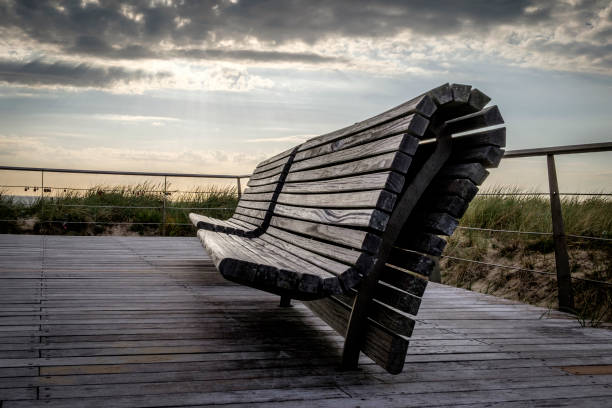 istock Curved wooden bench on the beach at sunset 1150800464