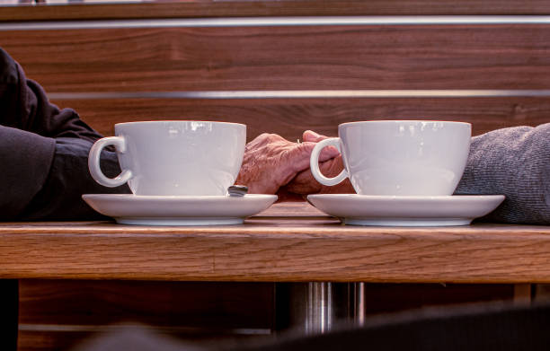 コーヒーを飲みながら保持している2つの手から写真を移動��する - care senior adult support human hand ストックフォトと画像