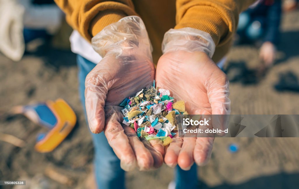 Hands with microplastics on the beach Detail of hands showing microplastics on the beach Microplastic Stock Photo