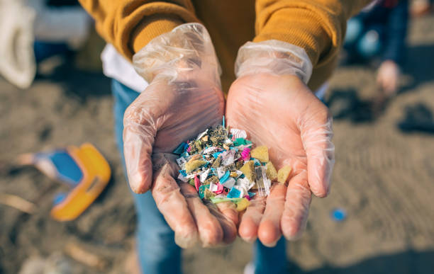 Hands with microplastics on the beach Detail of hands showing microplastics on the beach microplastic stock pictures, royalty-free photos & images
