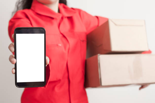 istock Image of a happy young delivery man in red cap standing with parcel post box isolated over white background. 1150805361