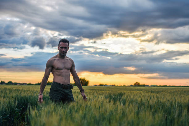 istock Man walking alone on a green meadow at sunset 1150806558