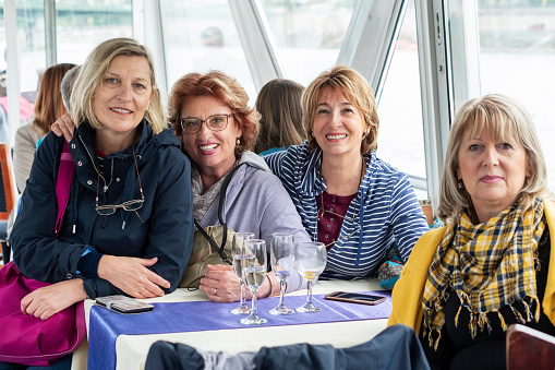 Senior women sitting  in a deck cabin of a cruise ship and exploring the city.
