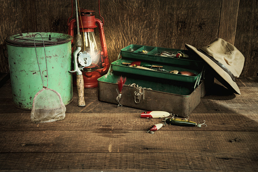 Vintage fishing gear with lantern on rough wood background