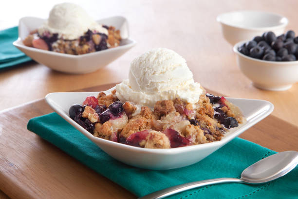 Blueberry Cobbler two blueberry cobblers with ice cream and extra blueberries cobbler dessert stock pictures, royalty-free photos & images