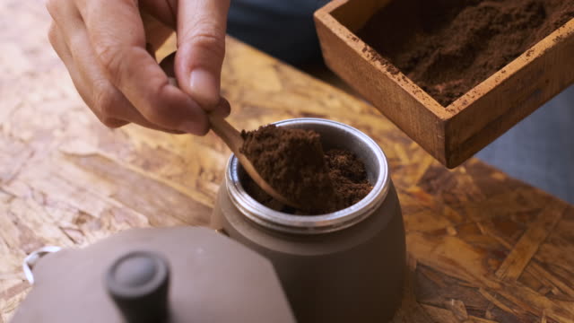 cu slow motiopn hand put fresh ground morning coffee powder in to coffee tablet of moka pot.