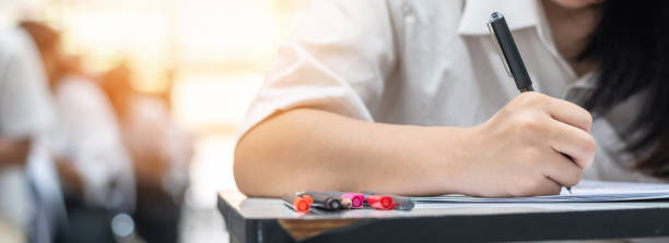 istock Exam student's taking educational admission test in school class, thinking hard, writing answer in university classroom, education and world literacy day concept 1150859746