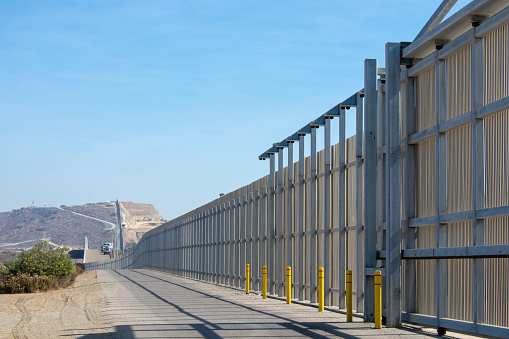 The border wall on the United States - Mexico international border near San Diego in California under blue sky