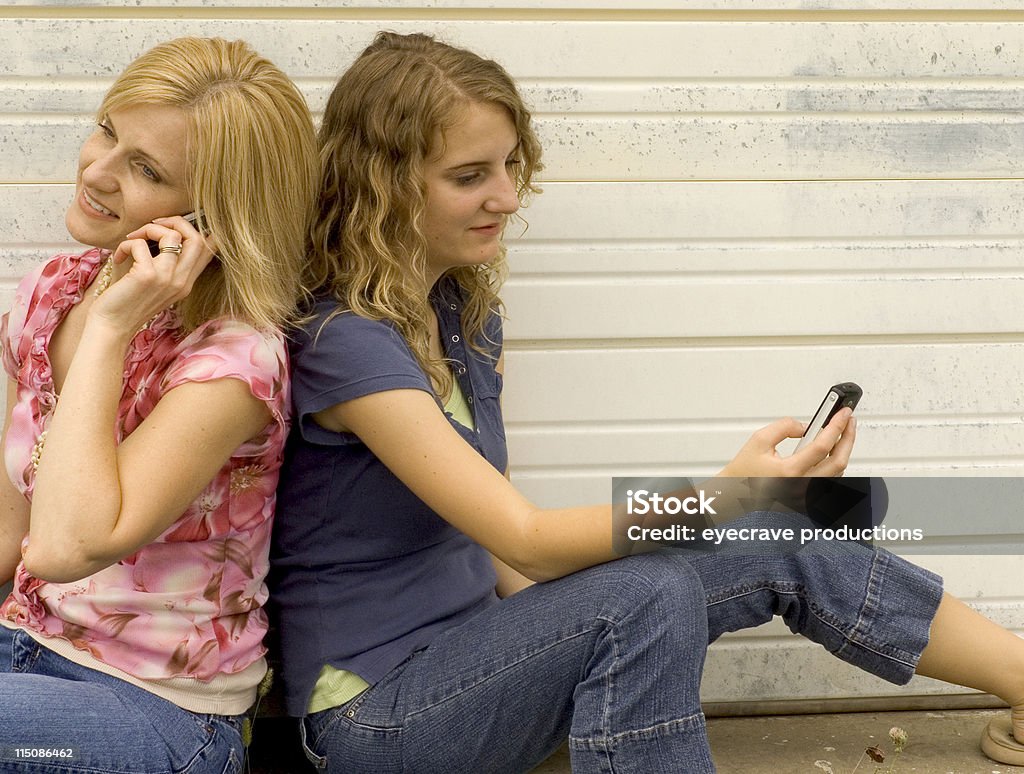 communication scenes - back-to-back calls teen girl and young woman with backs against each other making phone calls Adolescence Stock Photo