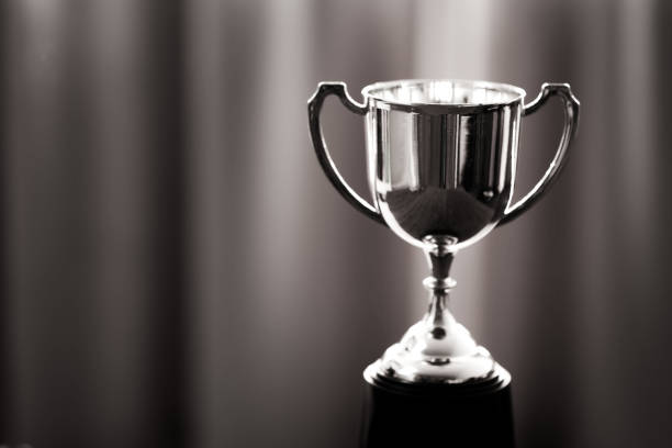 3D rendered Gold trophy award with shiny red stars on blue gradient background. Large copy space. Also can be used as square composition.