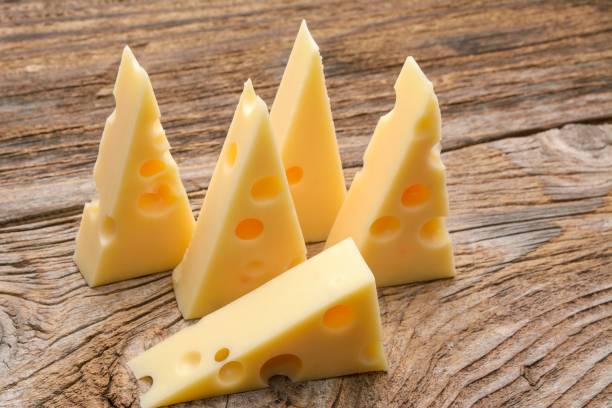 käse mit löchern groß und klein auf holzhintergrund - cheese emmental cheese swiss culture cutting board stock-fotos und bilder