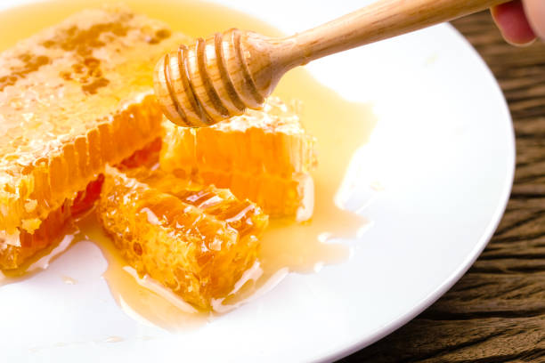 istock Honeycomb dipper and honey on white plate on wood background 1150868211