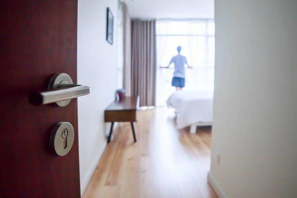 istock Young man looking through the window in an apartment bedroom 1150869139