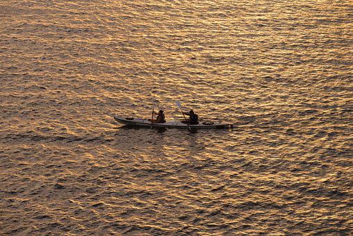 Two people paddling in a kayak at the sea of ​​cortes in a summer sunset, in the bay of La Paz, Baja California Sur State. Mexico