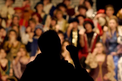 silhouette of Renaissance musical director in high school with student choir in background