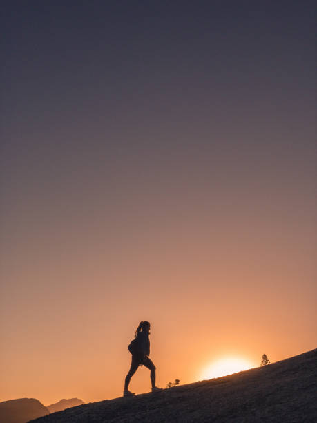 istock Young woman walks down mountain at sunrise 1150875091